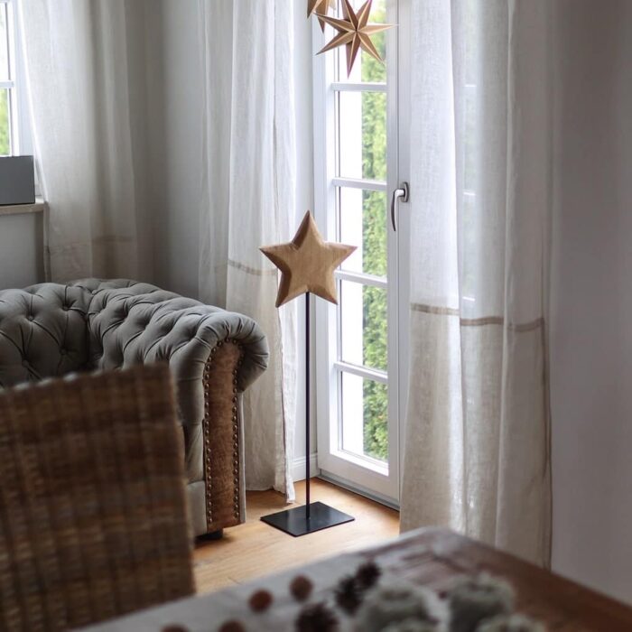 Eichenholzstern auf hohem Metallfuss dekoriert neben einem Sofa im Esszimmer